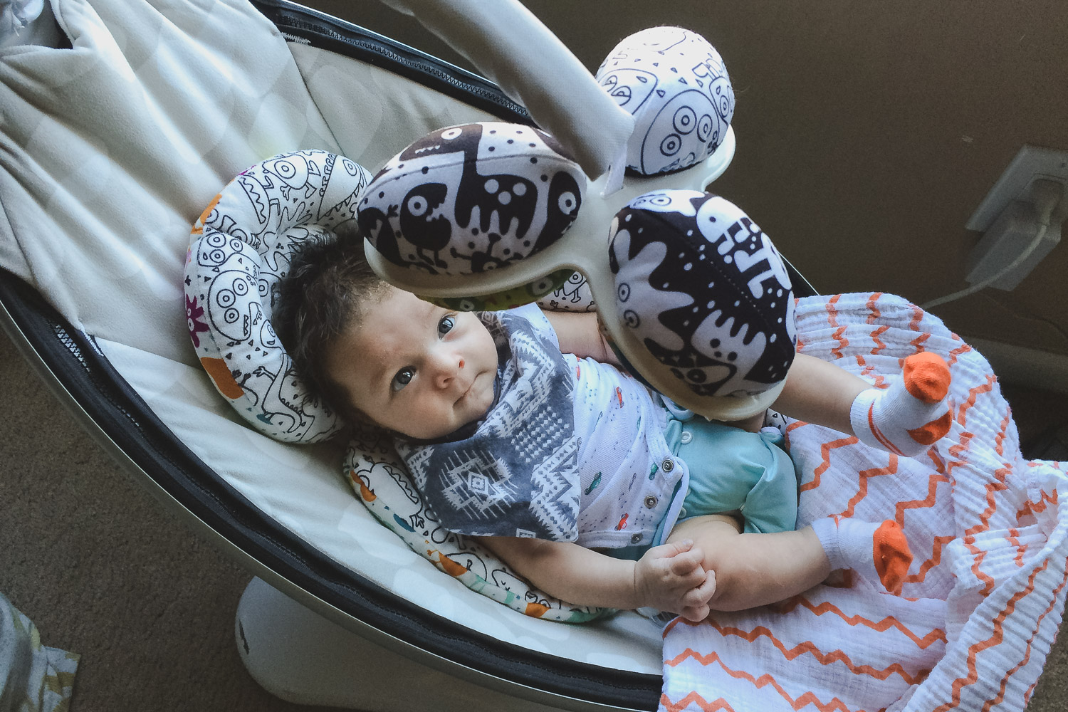 Newborn baby sitting in a mamaroo rocker swing wearing a cloth diaper and handkerchief. What baby items do you really need?