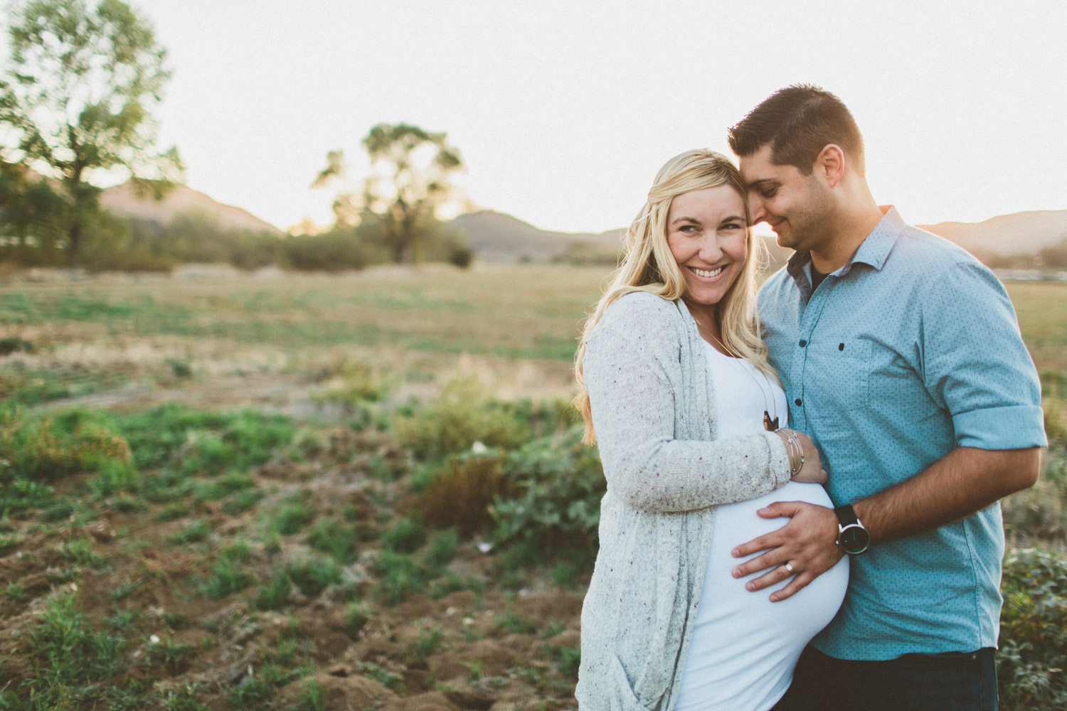 Pregnant wife with husband taking maternity photos.